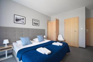 a bedroom with a large bed with blue and white sheets at Villa Nautica in Mrzeżyno