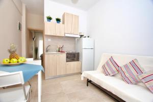 a living room with a white couch and a kitchen at Lovely apartment by the sea..... in Epanomi
