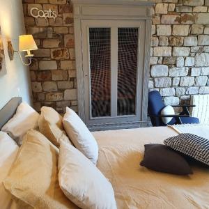 a bedroom with a bed with pillows and a brick wall at B&B Maison Pierreuse in Sart-lez-Spa