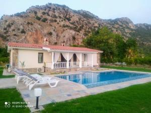 a house with a swimming pool in front of a mountain at Villa Narlibahce in Ortaca