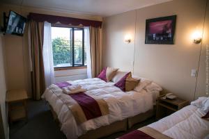 a hotel room with two beds and a window at Hotel Glaciares in Puerto Natales