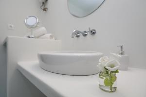 een badkamer met een wastafel en een vaas met bloemen bij Skopelos Aerino house in Skopelos Town