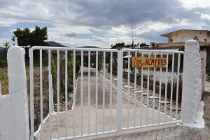 Um portão branco com um sinal de nós. em Los Almyros em Míloi