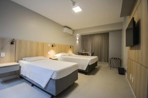 a hotel room with two beds and a flat screen tv at Garvey Park Hotel in Brasilia