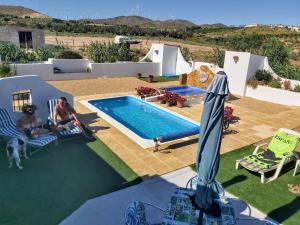 a couple sitting in lawn chairs next to a swimming pool at Casa con Vistas in Serón