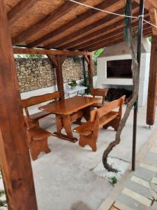 Apartments Sikirica في تروغير: طاولة وجلسة خشبية تحت بروغولا خشبي