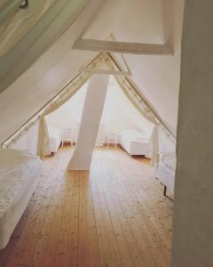 a attic bedroom with white beds and a wooden floor at Villa Vemmentorp - Körsbärsblomsvillan 6 min från havet in Skurup