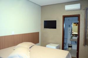 ein Schlafzimmer mit einem Bett und einem TV an der Wand in der Unterkunft Hotel Grutta in Bom Jesus da Lapa