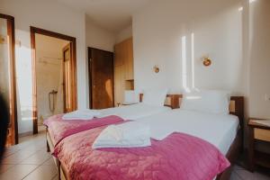 - une chambre avec 2 lits avec des draps roses et blancs dans l'établissement House of Gardenia, à Makrirrákhi