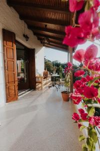 - une terrasse couverte avec des fleurs roses sur le côté de la maison dans l'établissement House of Gardenia, à Makrirrákhi