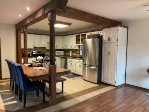 una cucina con tavolo e frigorifero in acciaio inox di Cheerful 4-bedroom cottage in nature setting a Waubaushene