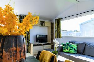 a living room with a couch and a vase with yellow flowers at Kustpark Nieuwpoort in Nieuwpoort +18 photos