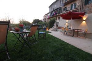 un patio con mesa, sillas y sombrilla en IL PICCINO 29, Esperienza Romantica in Borgo...., en Montescudaio