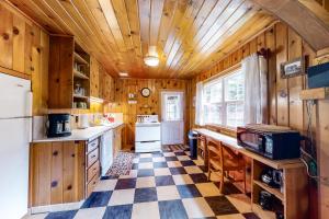 a kitchen with wooden walls and a checkered floor at River's Edge Cabin in Joseph