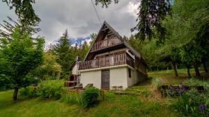 una casa con techo de gambrel en la parte superior de un campo en Holiday house Nature, en Ravna Gora