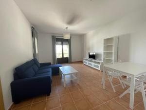 sala de estar con sofá azul y mesa en Apartamentos Los Senderos de Tolox, en Tolox