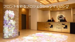 a lobby with two people sitting at a counter with a flower arrangement at Henn na Hotel Kanazawa Korimbo in Kanazawa