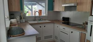 a kitchen with white cabinets and a sink and a window at Zen Latitude maison chaleureuse avec jacuzzi et plage à 800 m in Sainte-Anne