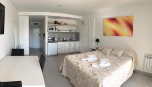 a bedroom with a large bed and a kitchen at Las Barrancas Apart & Spa in Necochea