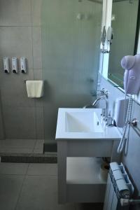 La salle de bains est pourvue d'un lavabo blanc et d'une douche. dans l'établissement Las Barrancas Apart & Spa, à Necochea