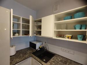 cocina con armarios blancos y fregadero en Castle Town Apartment, en Kaunas