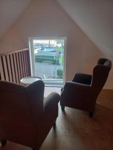 2 sillas y una mesa en una habitación con ventana en B&B De Kaagse Boer en Kaag