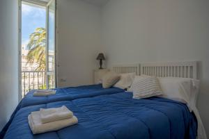 Una gran cama azul con toallas encima. en Apartamentos El Capitan Veneno by Cadiz4Rentals, en Cádiz