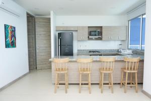 una cocina con 4 taburetes y una barra en Magico Apartamento Frente al Mar 3 Habitaciones PAZ282, en Coveñas