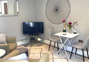 uma sala de estar com uma televisão e uma mesa com cadeiras em The Lodge Chester - luxury apartment for two, with free parking! em Hough Green