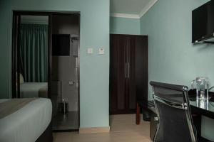 Cette chambre comprend un lit et un bureau avec une télévision. dans l'établissement PeaconWood Boutique Villa, à Palatswe