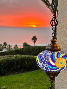 a colorful vase hanging from a chain with a sunset in the background at Puerto Velero Primera Línea Primer Piso con Jardín, Piscina y Playa! 7pax in Puerto Velero