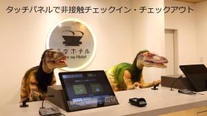 Henn na Hotel Kanazawa Korimbo في كانازاوا: اثنين من تماثيل الديناصورات جالسين بجوار طاولة مع الكمبيوتر المحمول