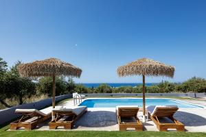 a swimming pool with chairs and umbrellas at Gramvella Resort in Adelianos Kampos