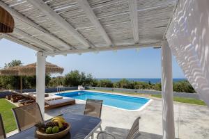 a villa with a swimming pool and a table and chairs at Gramvella Resort in Adelianos Kampos