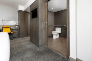 a bathroom with a toilet and a television on the wall at M Social Hotel New York Times Square in New York