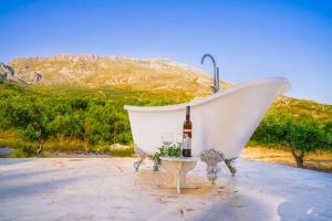 Bungalows Panstel in Kerames Rethymno في Agia Paraskevi: حوض استحمام أبيض مع زجاجة من النبيذ وكأس