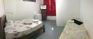 a room with two beds and a television in it at Pousada flor de Atibaia in Atibaia