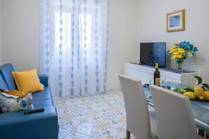 un soggiorno con tavolo, sedie e TV di Casa Vacanza La Gardenia a Tramonti