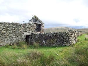 uma antiga casa de pedra com uma parede de pedra em The Old School B&B em Tebay