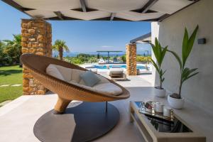a wicker chair on a patio with a pool at Iakovakis Suites & Spa in Koropi