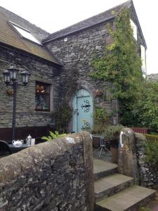 a stone house with a blue door and stairs at The Old School B&B in Tebay