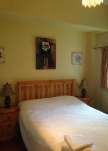 um quarto com uma grande cama branca e 2 candeeiros em The Old School B&B em Tebay