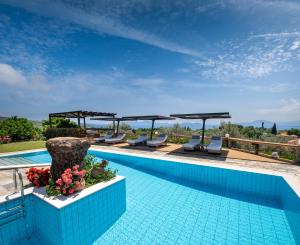a swimming pool with chairs and umbrellas at Iakovakis Suites & Spa in Koropi