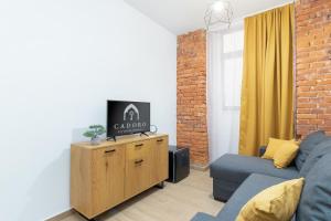 a living room with a couch and a tv on a cabinet at CADORO City Center Apartments in Oradea