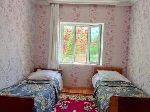 two beds in a room with a window at La Casa de Habel in Quba