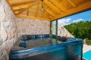 bañera de hidromasaje en un edificio de piedra con techo de madera en Luxury Villa Borak, en Imotski