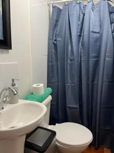La salle de bains est pourvue d'un lavabo et d'un rideau de douche bleu. dans l'établissement Cabañas Caur, à San Pedro de Atacama