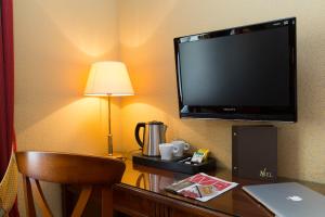 una camera d'albergo con scrivania, TV e lampada di Elysees Niel Hotel a Parigi