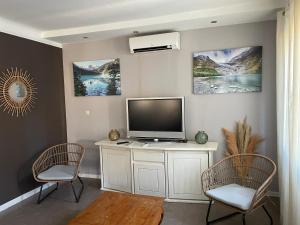 a living room with a television and two chairs at Appartement spacieux et lumineux Calanques Sormiou in Marseille