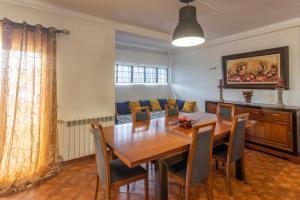 a dining room with a wooden table and chairs at Vivenda Esgravina in Sesimbra